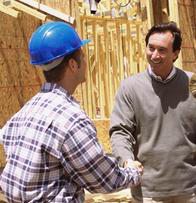 Two men shaking hands in front of a wall.