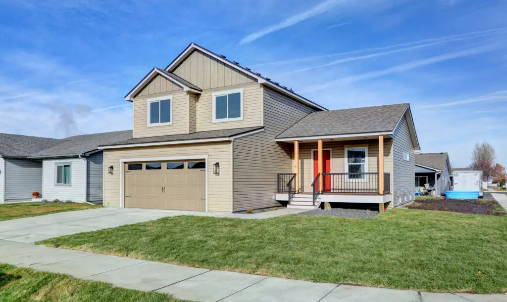 A house with a garage and porch in the front yard.